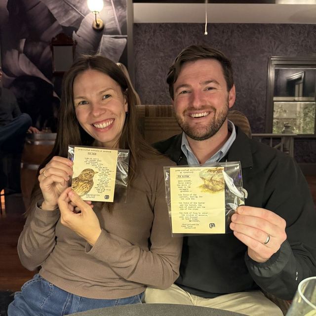 A couple holding the custom typewritten poems they received at Poem-crafted Cocktails at Speakeasy & Whiskey Bar