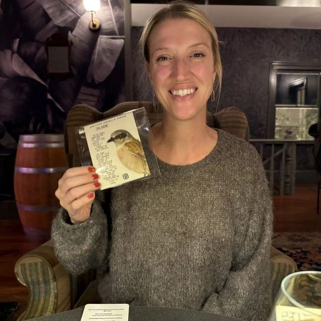 A smiling guest showing her custom typewritten poem at Poem-crafted Cocktails at Speakeasy & Whiskey Bar