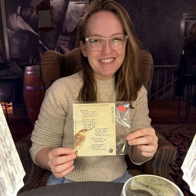A guest holding her custom poem in a clear envelope at Poem-crafted Cocktails at Speakeasy & Whiskey Bar