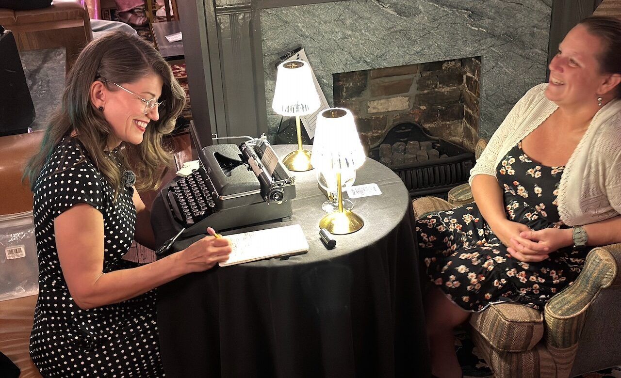 Laura Frantz typing a poem for a guest on a vintage typewriter by lamplight