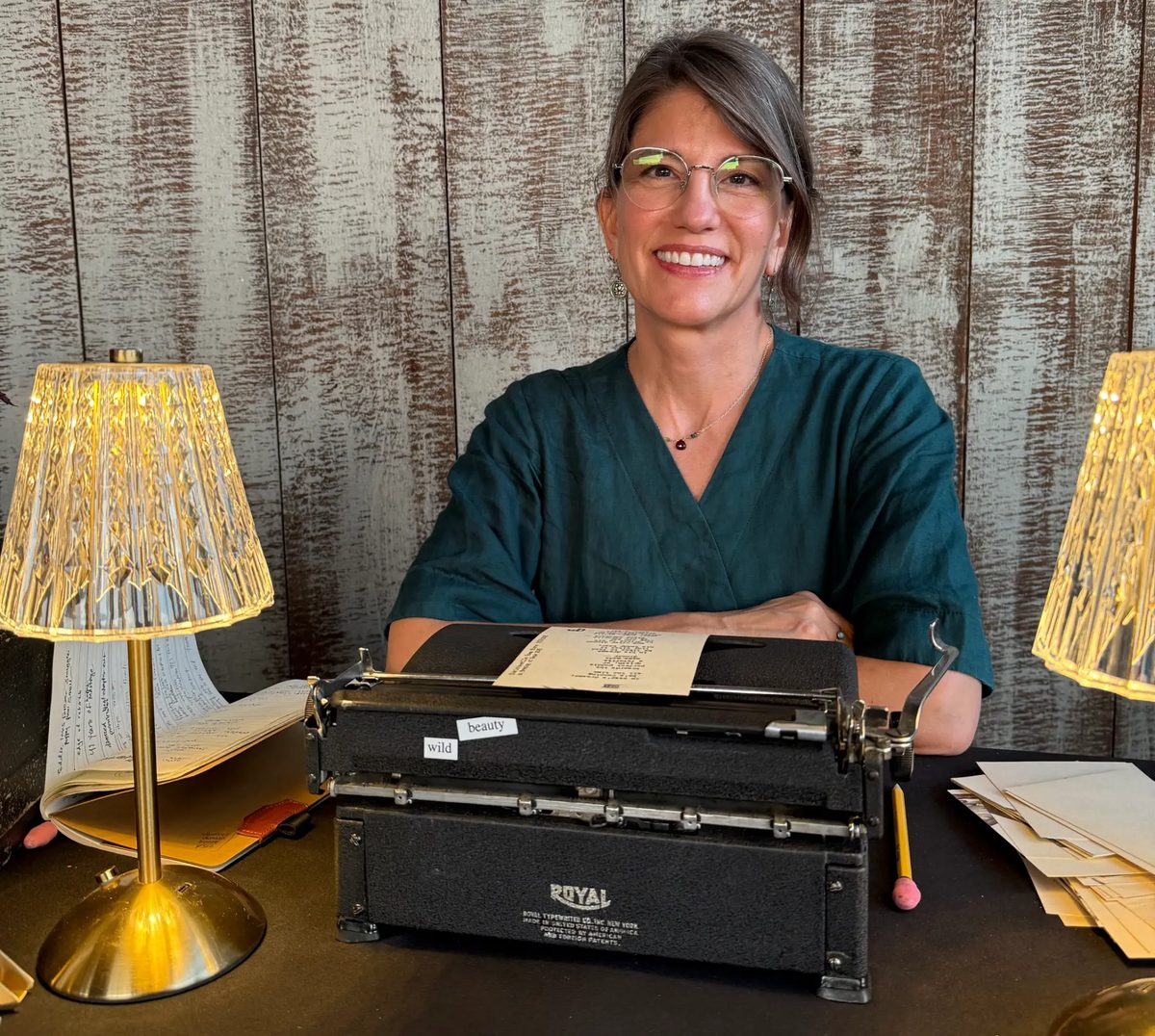 Laura Frantz smiling behind a Royal typewriter between two crystal lamps