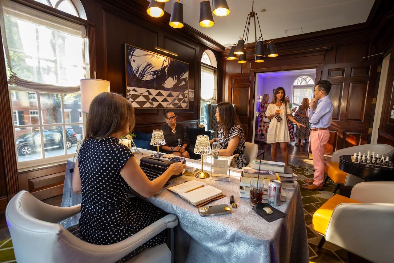 The poet typing at an event while guests mingle