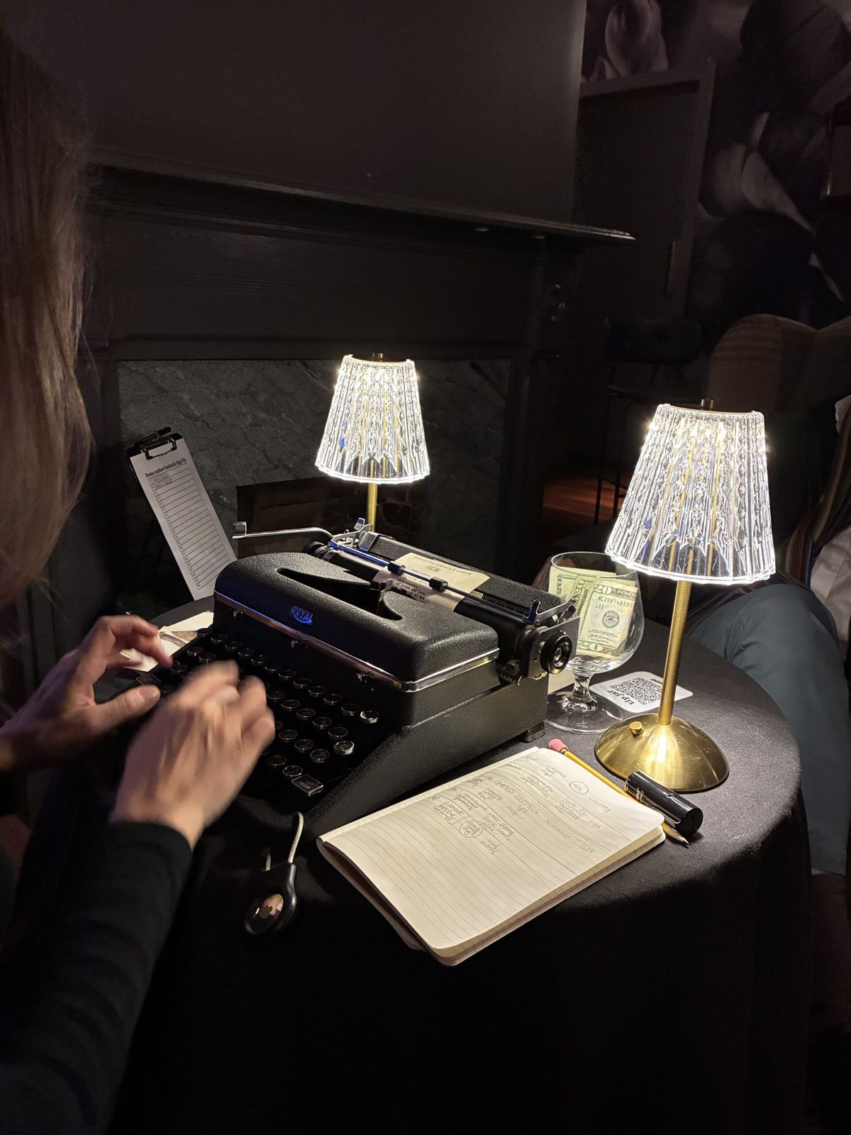 Hands typing a poem on a vintage typewriter beside a crystal lamp