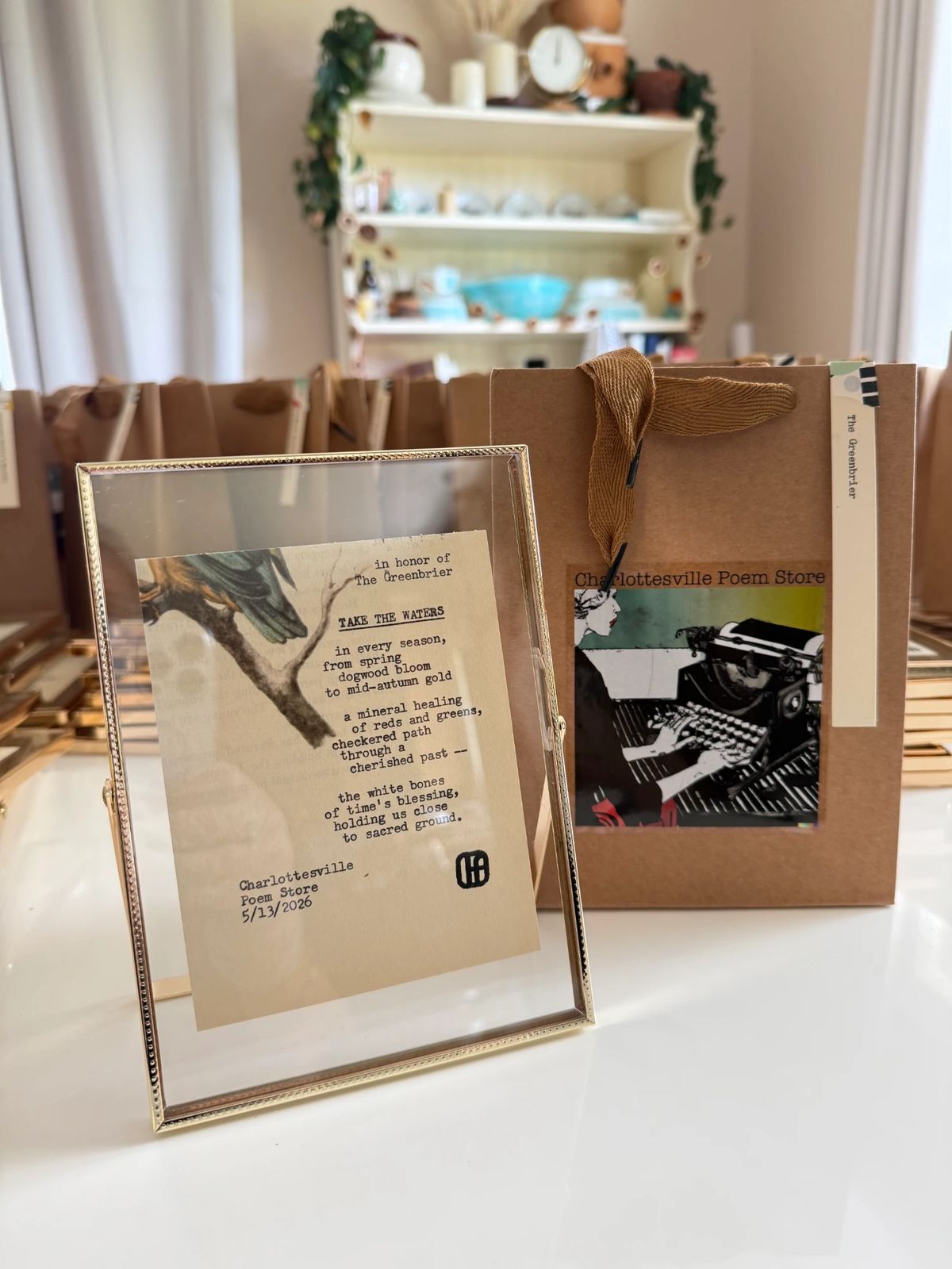 A framed typewritten poem, Take the Waters, written in honor of The Greenbrier, beside a Charlottesville Poem Store gift bag